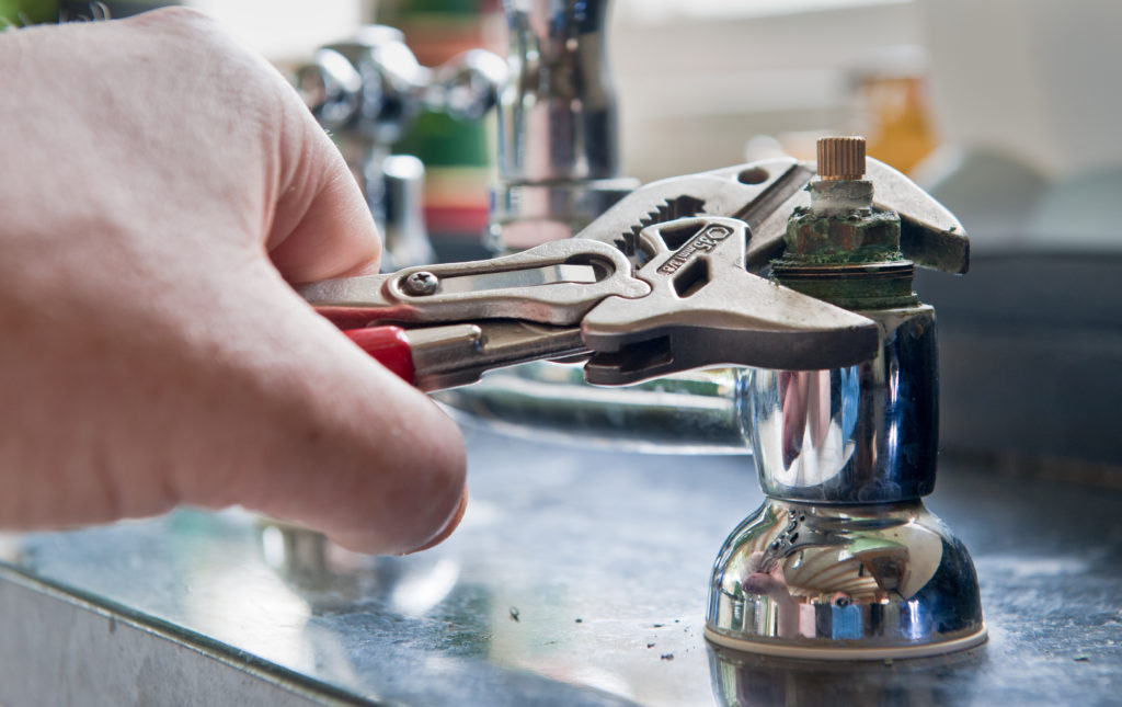 Real life situation - A plumber uses adjustable grips to remove a worn insert from a set of kitchen taps with a view to replace the damaged part.