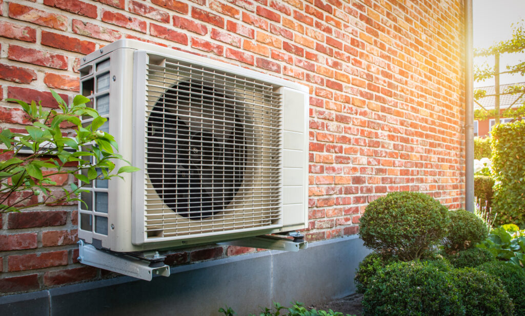Air conditioning heat pump outdoor unit against brick wall