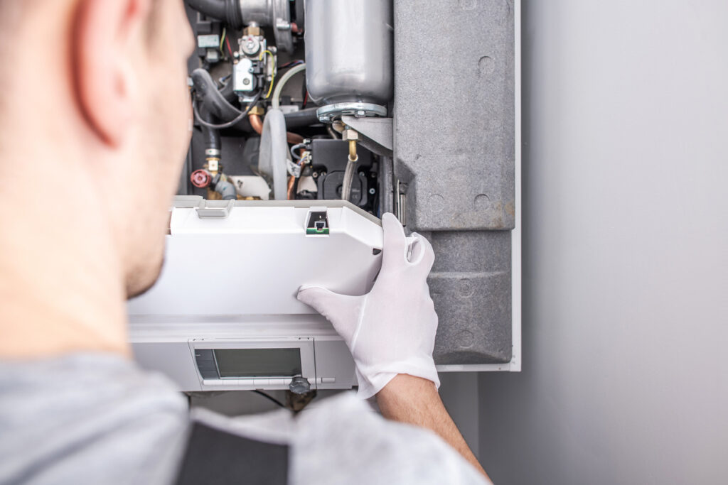 Close Up Of Worker Fixing Central Heating Furnace System.